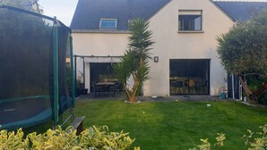 Une maison dotée d’un patio couvert, d’un trampoline et d’une pelouse bien entretenue.