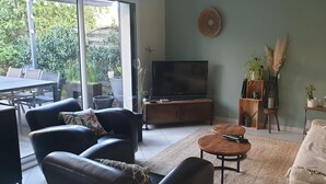 Un salon comprenant un canapé, une table basse, un téléviseur et un coin repas avec une table et des chaises.