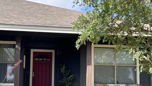 A house with a red door, a window with a view, and two wicker chairs outside. - Lake Time at Beautiful Buchanan (Burnet)