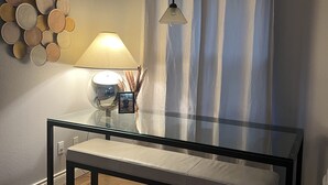 A room with a glass table, a bench, a lamp, a wall-mounted light fixture, and a curtain. - Lake Time at Beautiful Buchanan (Burnet)