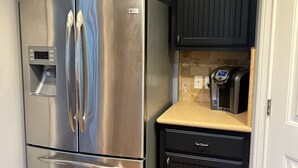 A stainless steel refrigerator with a water dispenser, black cabinets, a microwave, and a countertop. - Lake Time at Beautiful Buchanan (Burnet)