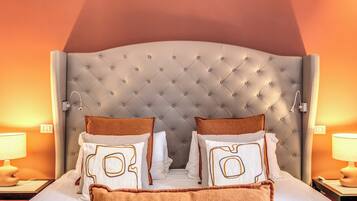 A neatly made bed with a tufted headboard, two pillows with a geometric design, and a brown throw blanket.
