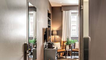 Ein modernes Hotelzimmer mit Sofa, kleinem Tisch, Lampe und Spiegel.