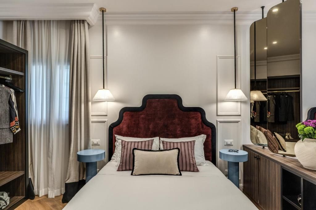 A bedroom with a large bed, two bedside lamps, a mirror, and a wardrobe.