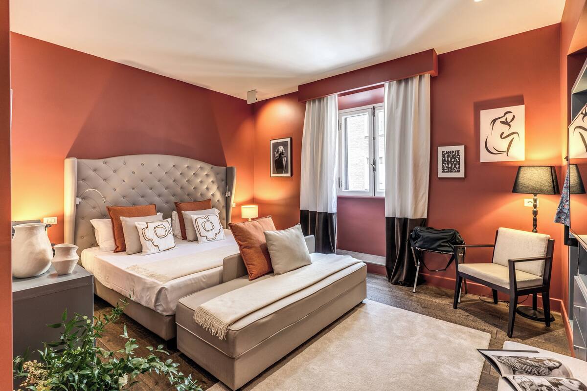 Un dormitorio moderno con una cama grande, mesitas de noche, una silla y obras de arte en las paredes.