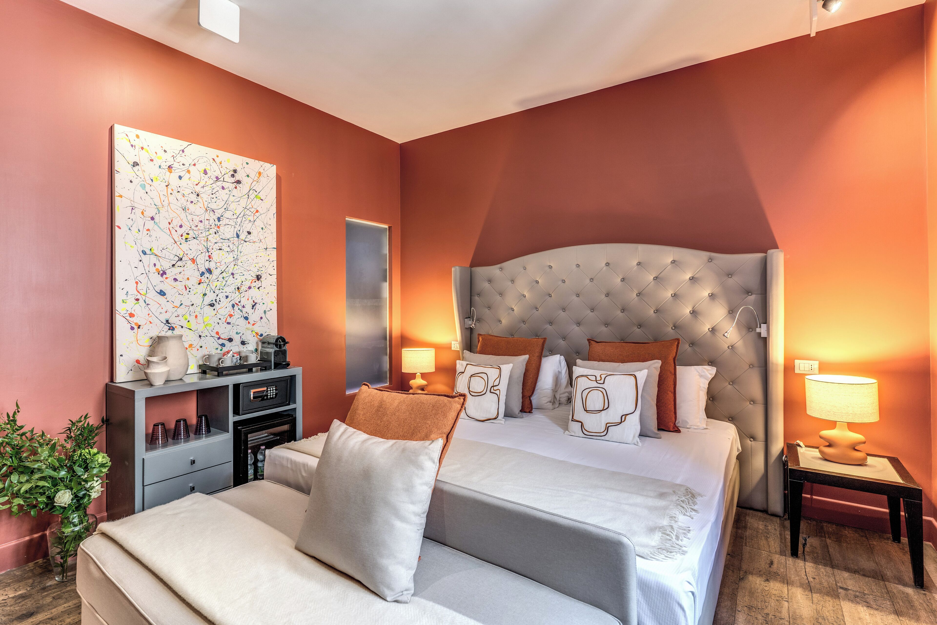 A modern hotel room with a large bed, two bedside tables with lamps, a dresser, and a large abstract painting on the wall.