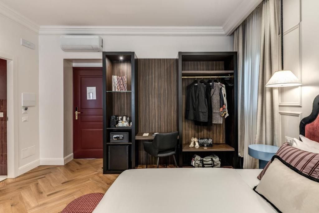 Une chambre d’hôtel comprenant un lit, un bureau, une armoire et un petit coin salon.