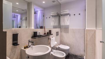 A modern bathroom with a large mirror, a sink, a bidet, and a toilet.
