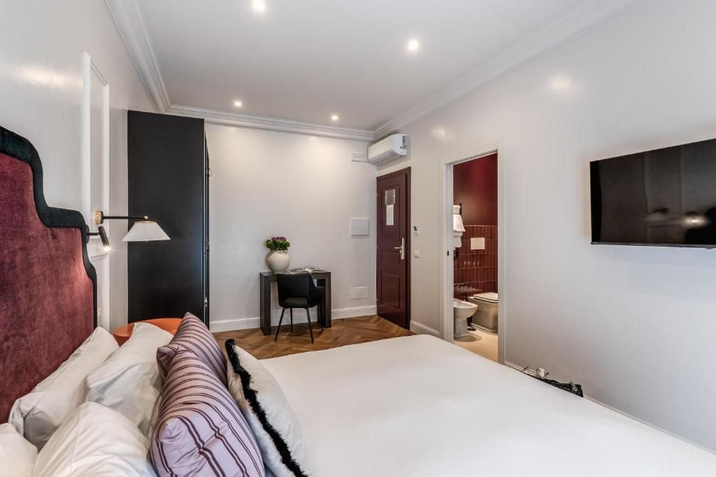Un dormitorio moderno con una cama, un escritorio y un televisor fijado a la pared.