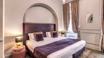 A neatly arranged bedroom with a large bed, a round side table, a nightstand, and a mirror on the wall.