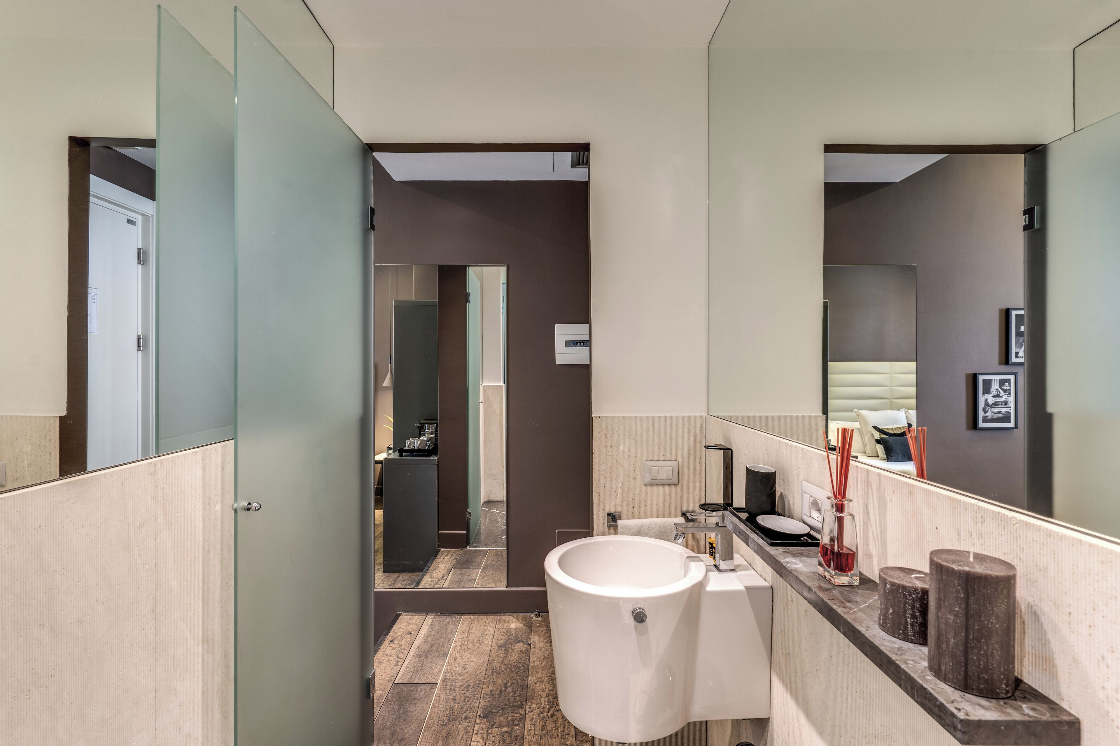 A modern bathroom with a large mirror, a white sink, and a shower area.