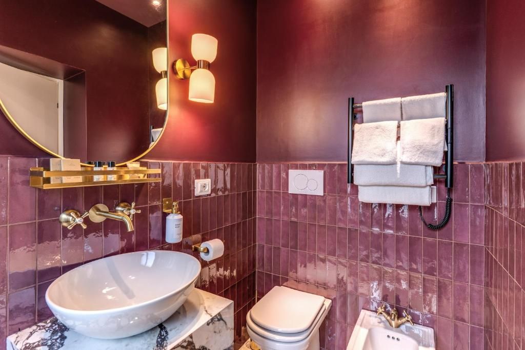 Une salle de bain avec un grand lavabo ovale, des toilettes, un miroir et un porte-serviettes.