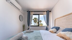 A bedroom with a bed, a window with curtains, a wall-mounted air conditioner, and a small potted plant. - Charming apartment near beach, sea view  REF038 (Torremolinos)