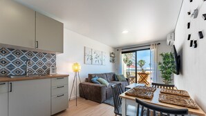 A modern kitchen with a geometric backsplash, a dining area with a round table and chairs, and a living area with a sofa and cushions. - Charming apartment near beach, sea view  REF038 (Torremolinos)
