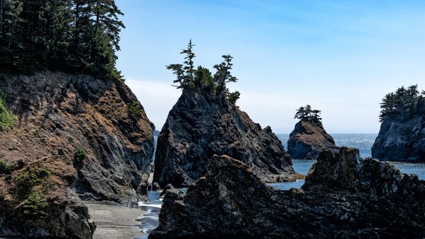 Un paisaje costero rocoso con aguas cristalinas y una playa arenosa.