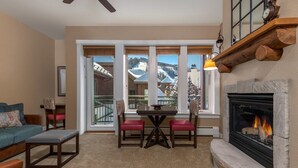 A cozy living room with a fireplace, a dining area with a table and chairs, and large windows offering a mountain view. - Hyatt Mountain Lodge Beaver Creek, Colorado - Prime Ski & Summer Weeks Available (Avon)