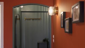 A bathroom with a glass door, a towel rack, a small plant, and framed pictures on the wall. - Volanaki4 - A happy 2 Bdr apartment that has a (Athens)