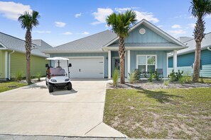 A two-story house with a garage, a driveway, and a golf cart parked in front. - Family-fun 4BR w/ pool, game room and golf cart (Port St. Joe)