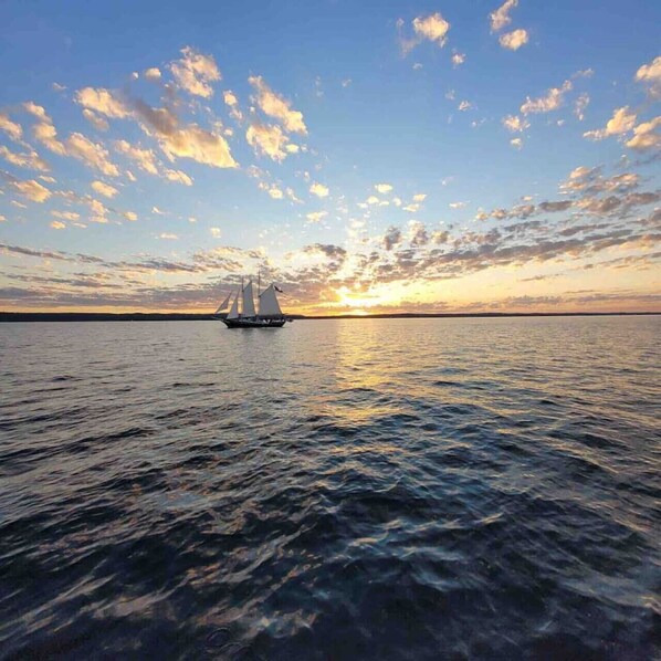 A sailboat on calm waters during sunset with a clear sky.