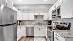 Una cocina moderna con armarios blancos, electrodomésticos de acero inoxidable y encimera de mármol.