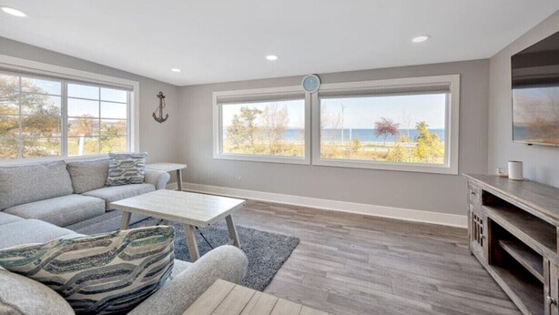 Una sala de estar moderna con sofá, mesa de centro y televisión, ventanas amplias con vistas al exterior.