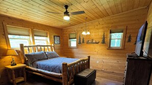 A wooden cabin bedroom with a bed, a nightstand, a dresser, and a ceiling fan. - Secluded Upscale Smoky Mountain Retreat - Hot Tub, Game Room,  Near Pigeon Forge (Sevier County)