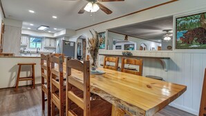 A spacious kitchen with wooden chairs and a large dining table, a ceiling fan, and a window with natural light. - Secluded Upscale Smoky Mountain Retreat - Hot Tub, Game Room,  Near Pigeon Forge (Sevier County)