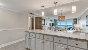 A spacious kitchen with a large island, white cabinetry, and pendant lighting.