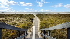 A wooden boardwalk leading to a beach with a clear sky.