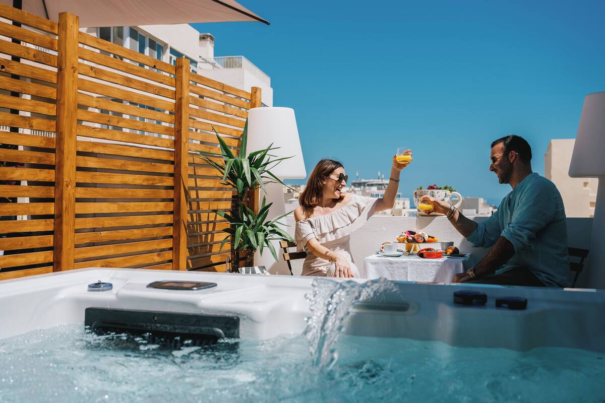 A couple enjoying a meal at a table with a hot tub in the foreground.