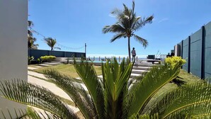 A pool area with a view of the ocean, palm trees, and a person standing by the pool. - Villa Marr, Beachfront House in La Libertad (San Salvador)