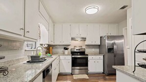 A modern kitchen with white cabinets, stainless steel appliances, and granite countertops. - Palmetto Retreat/Centrally Located/Near FLETC (Brunswick)