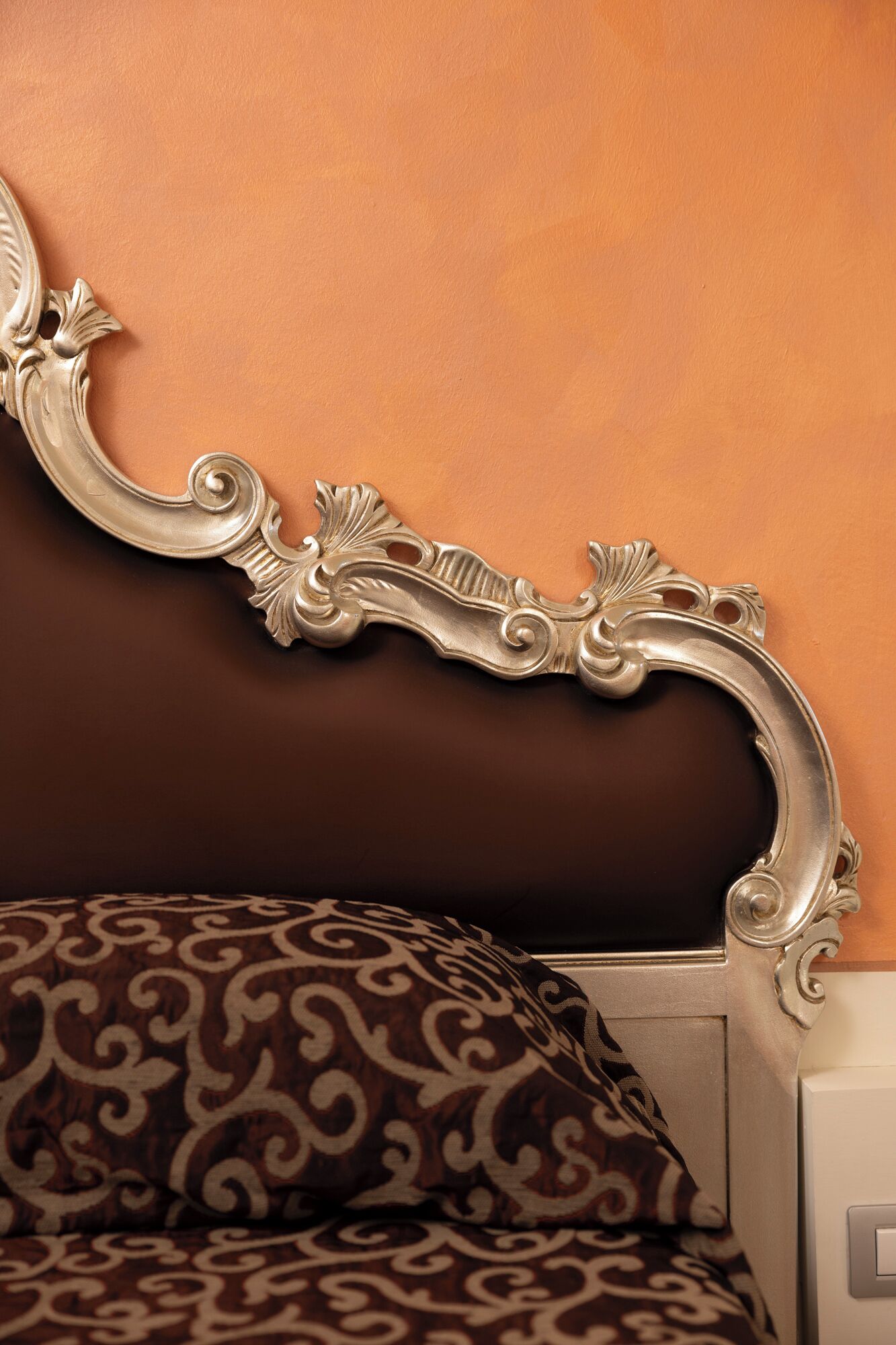 Un lit avec une tête de lit décorée, placé contre un mur sobre.