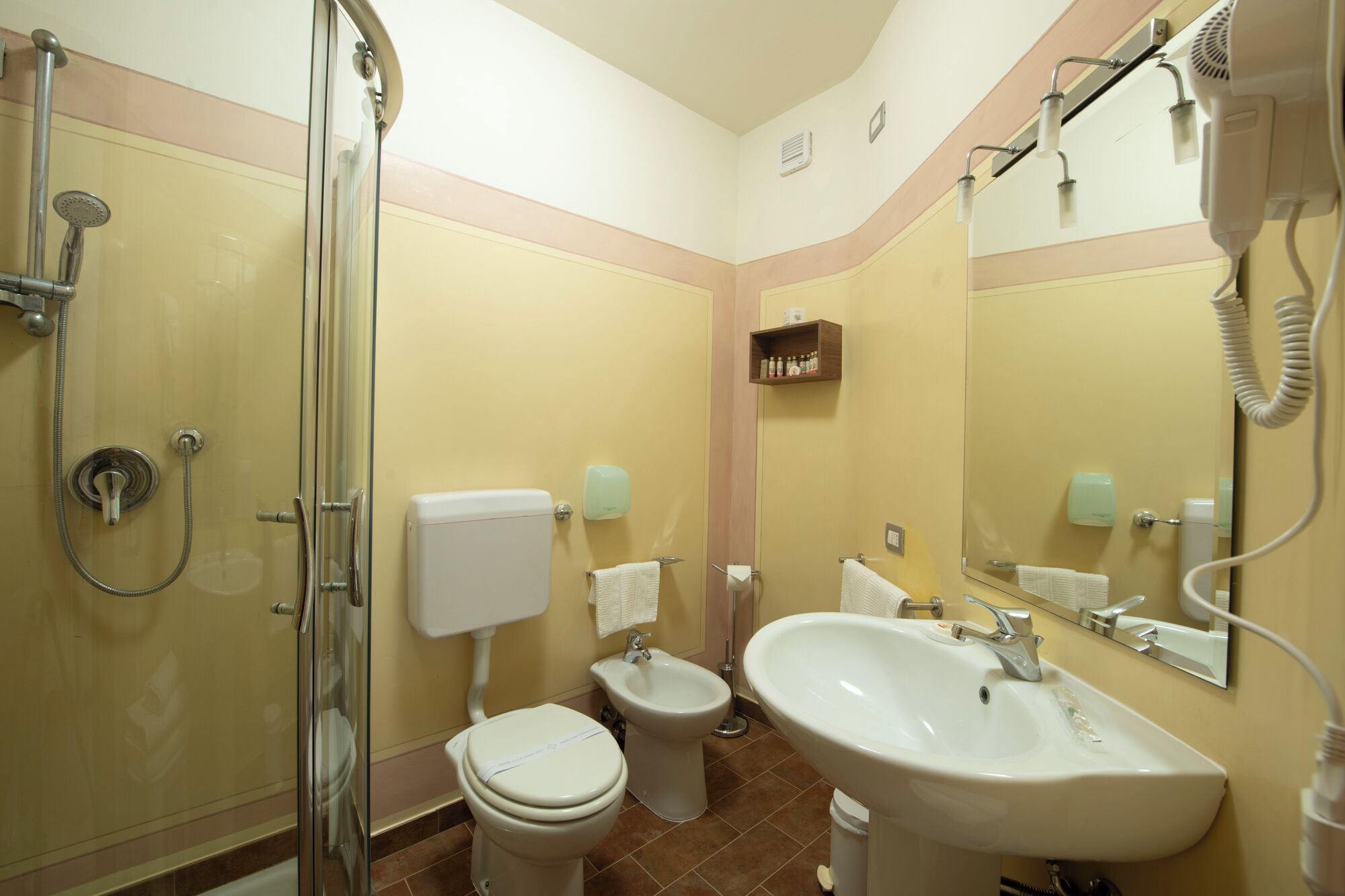 Une salle de bain avec une douche à parois de verre, des toilettes, un bidet et un lavabo.