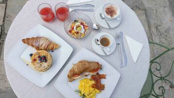 A table set with breakfast items including croissants, scrambled eggs, and a croissant sandwich, along with drinks and cutlery.