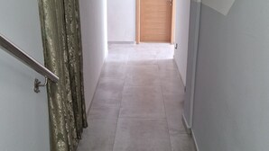 Un escalier mène à une porte en bois au bout d’un couloir, et un interrupteur est fixé au mur.