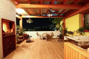 An outdoor patio with wooden flooring, a ceiling fan, and a table with chairs. - Guesthouse Rose (Sarajevo)