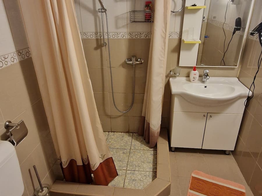 Ein Badezimmer mit Dusche, Toilette, Waschbecken und Spiegel.