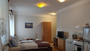 Une chambre comprenant un lit, un bureau, une armoire et une kitchenette équipée d’une cuisinière et d’un four.