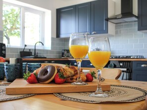 A breakfast setting with croissants, strawberries, and orange juice glasses on a wooden table.