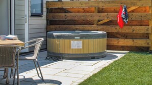 A hot tub, patio furniture, and a wooden fence in a residential setting.