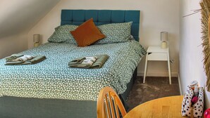 A bedroom with a bed, a nightstand, a chair, and a small table.