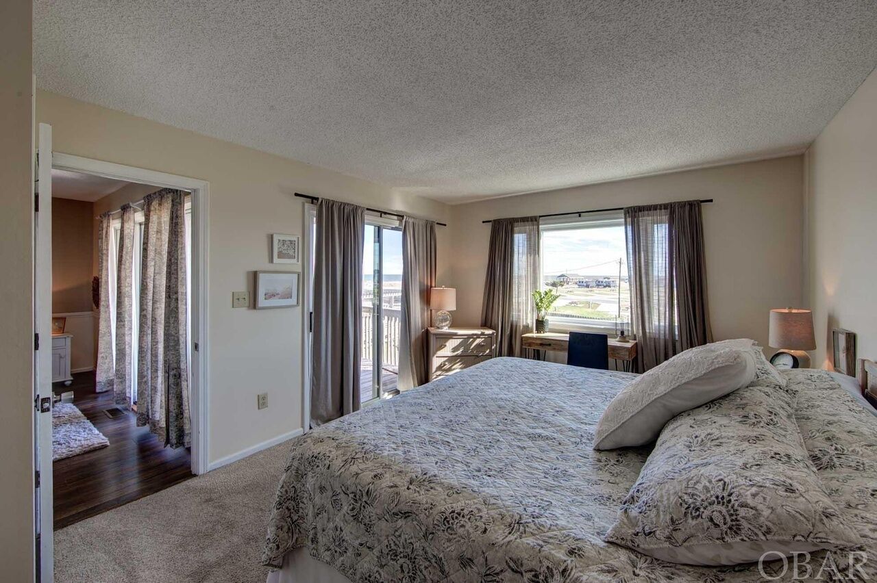Une chambre avec un grand lit, deux tables de chevet, un bureau et une vue sur l’extérieur.