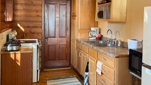 A kitchen with wooden cabinets, a stove, a sink, and a microwave.