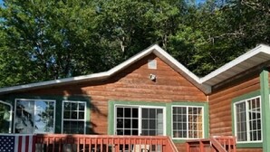 A wooden cabin with a porch, large windows, and a flag.