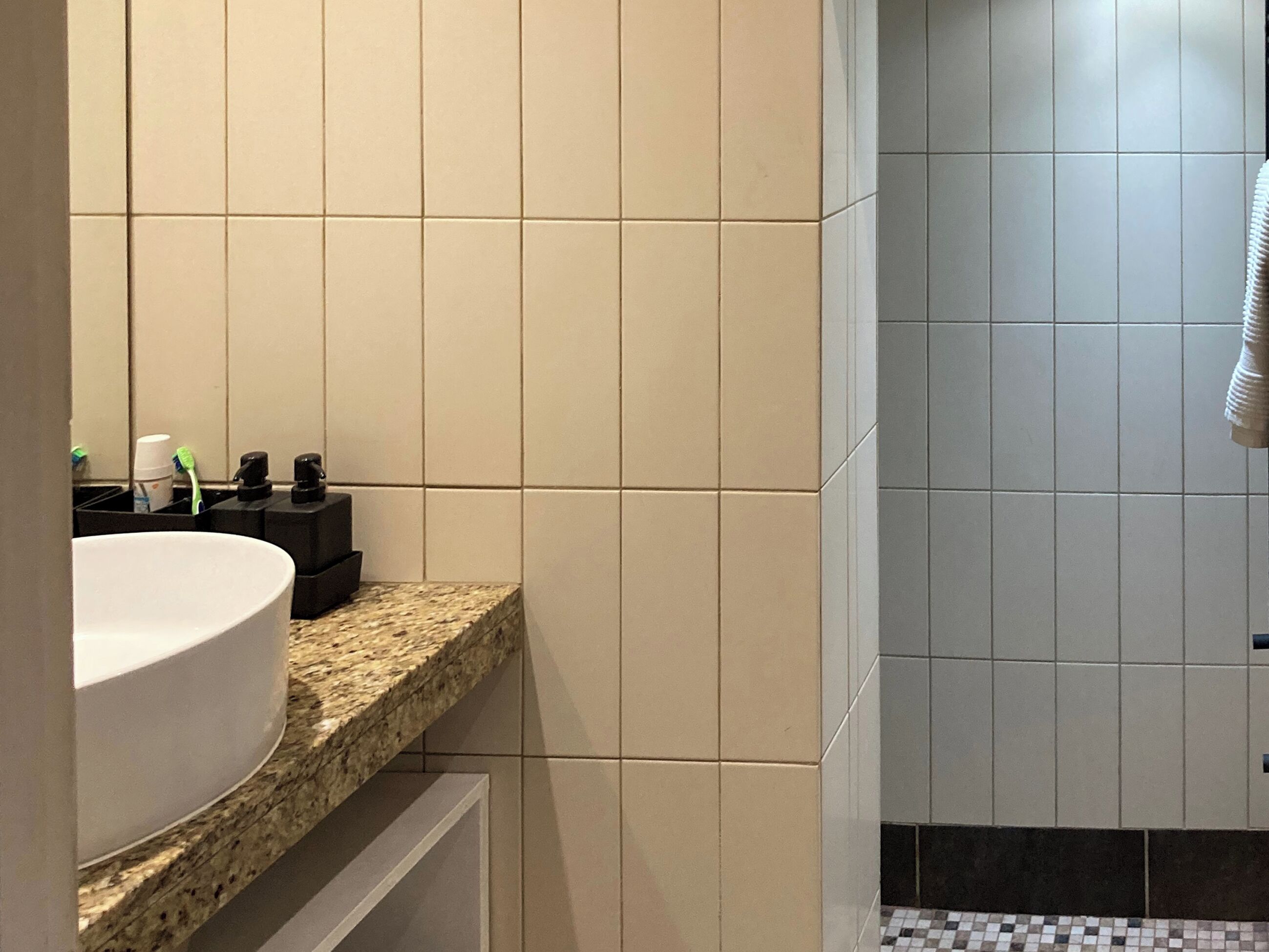 A bathroom with a white sink, a mirror, and a tiled shower area.