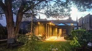 Una casa moderna con una entrada luminosa, rodeada de árboles y un jardín.