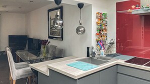 Una cocina moderna con una isla integrada, un comedor con mesa de vidrio y una pared decorada en rojo.