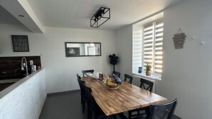 A modern kitchen with a wooden dining table, black chairs, and a white countertop.