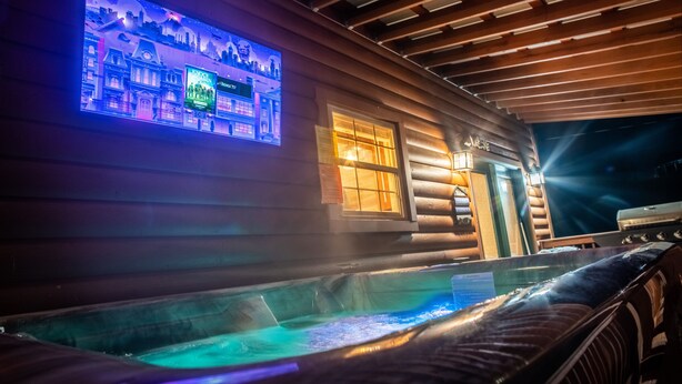 A log cabin with a hot tub, wooden walls, and a lit-up display. - Lake side retreat- Huge game room, hot tub fire pit and more! (Sevierville)